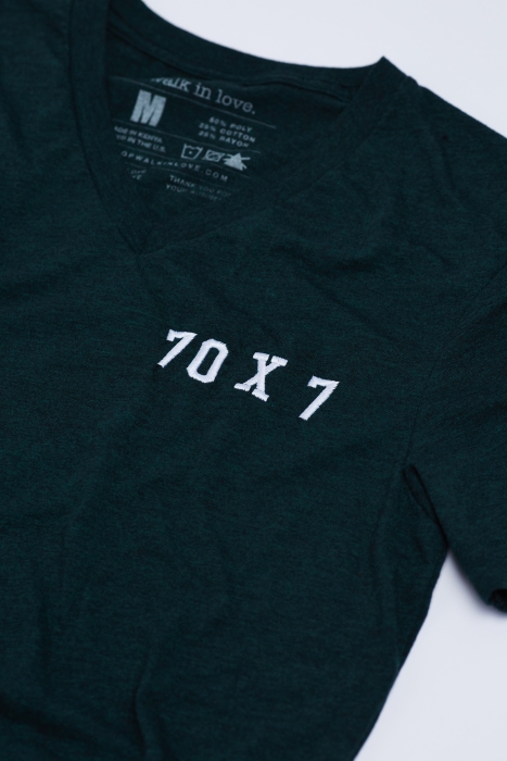 Close up of '70 X 7' embroidered on a green v-neck t-shirt by walk in love.
